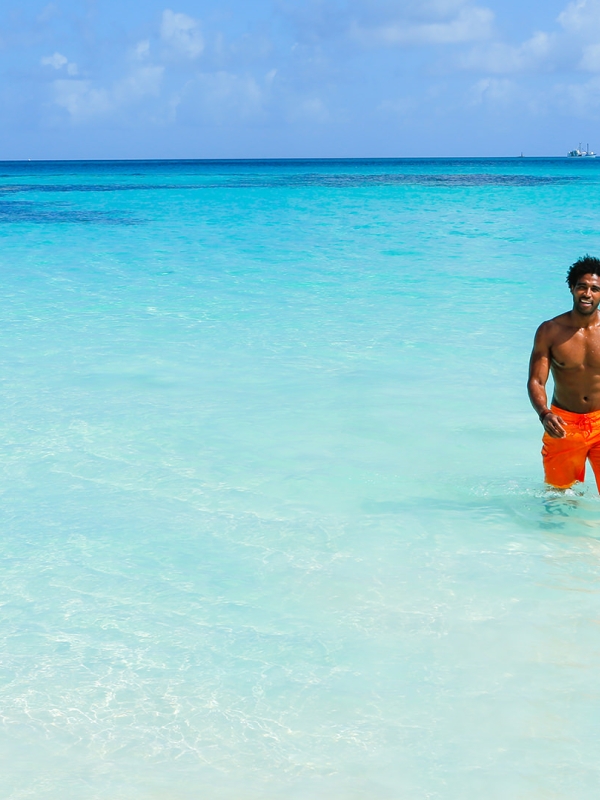 A man and woman holding hands while standing in the water together.